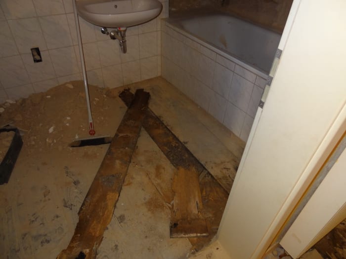 Geöffneter Badezimmerboden im Raum Erlangen mit freigelegten, durch den Echten Hausschwamm zerstörten Holzbalken